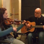 Sarolta playing violin and David playing acoustic guitar